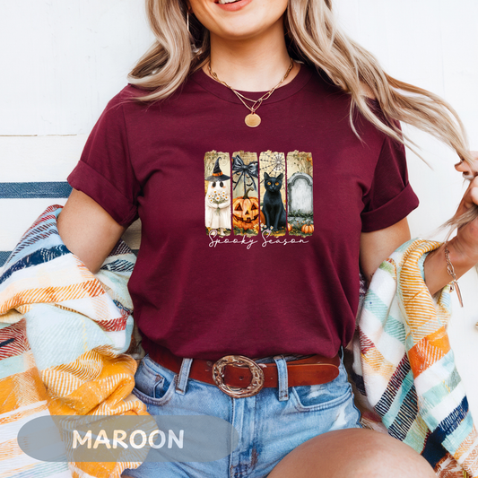 Cute Halloween T-Shirt featuring black cat, pumpkin, and spooky decorations on a maroon background.